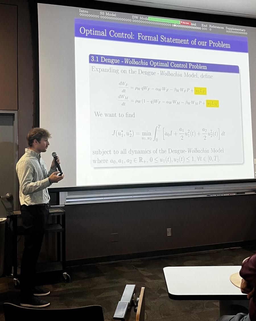 Evan Gibbs stands next to a presentation on Dengue Wolbachia Model for mosquitoes