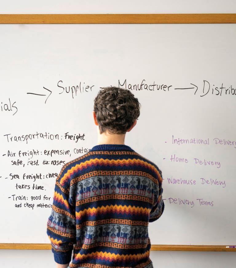 A student is studying supply chain materials on a white board.