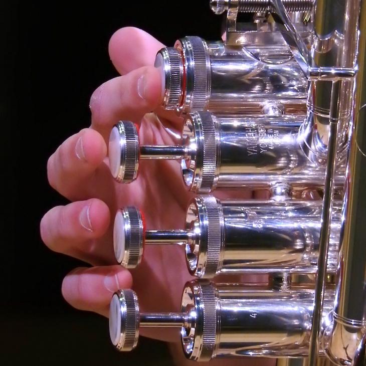 A close-up image shows fingers playing a trumpet.