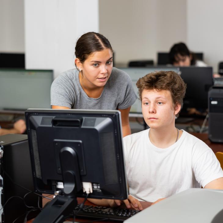 A teacher helping a student at a computer.