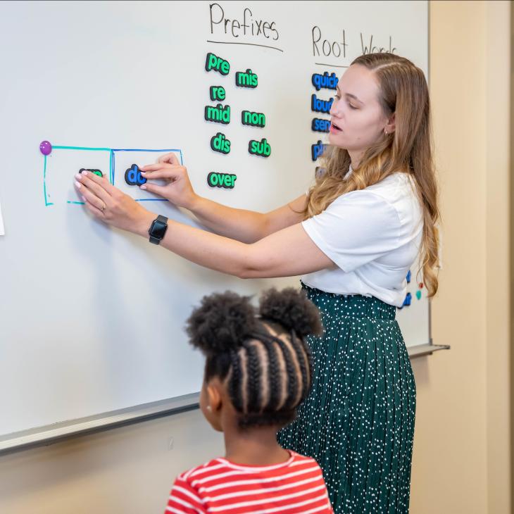 A student teacher teaching two students at the whiteboard.