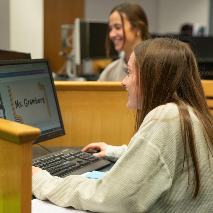 A student sits at a computer and works on a presentation in the Schmidt Library