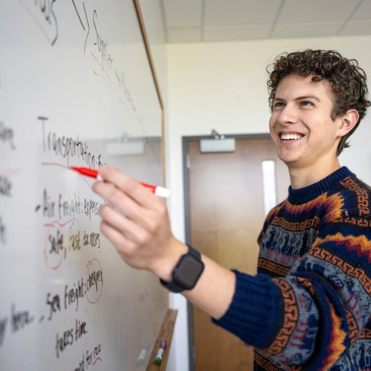 A Student is writing on a whiteboard during a study session