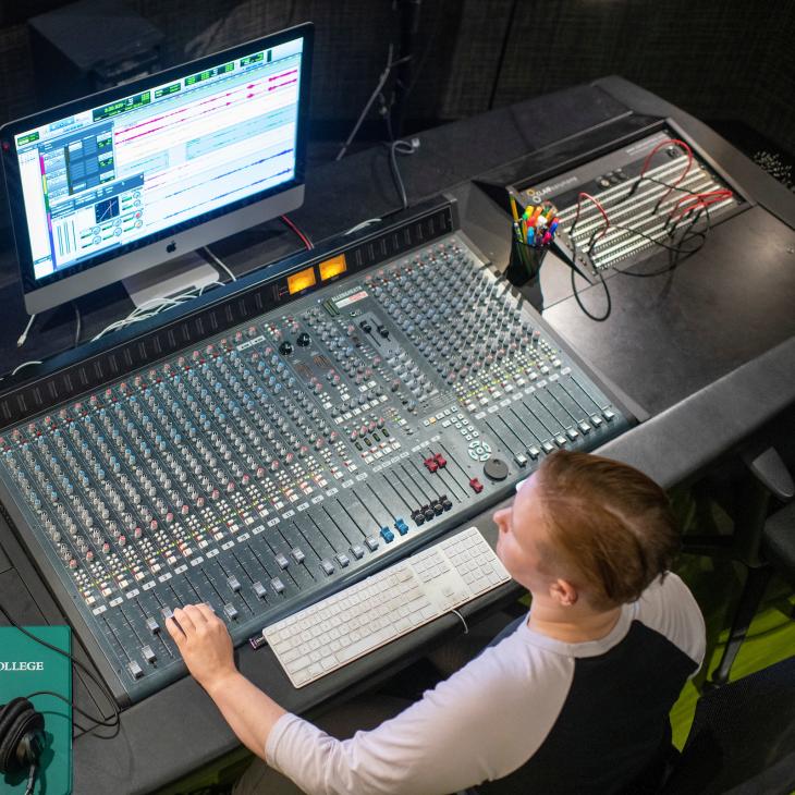 A student works at a recording studio soundboard.