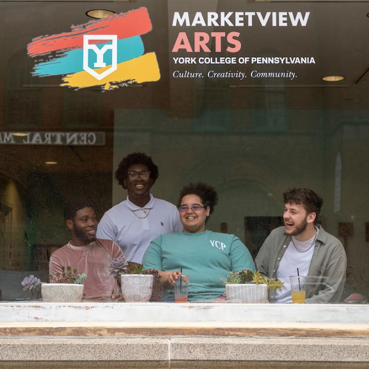 4 students in Marketview Arts with the shop in the background.