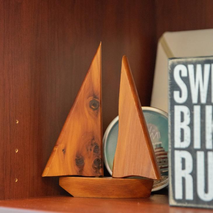 A small wooden sailboat sits on a shelf.