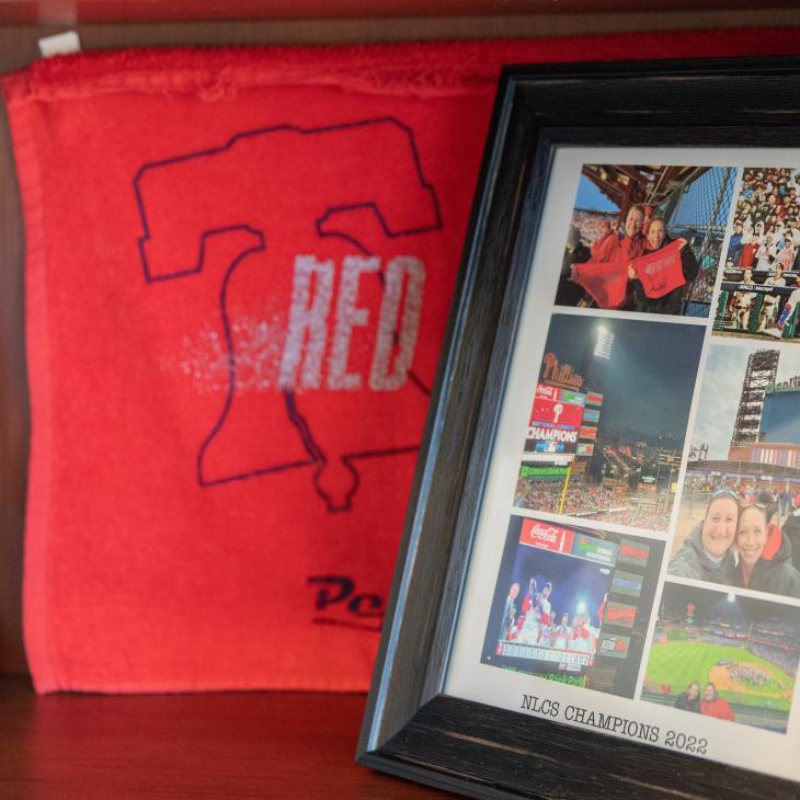 A red towel sits beside a framed photo collage on a shelf.