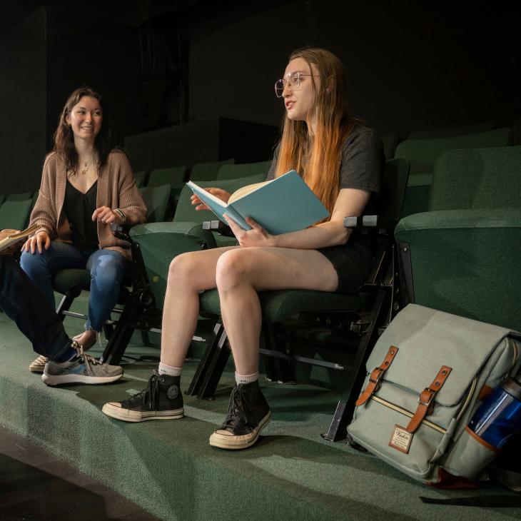 Two students reading scripts in the theatre