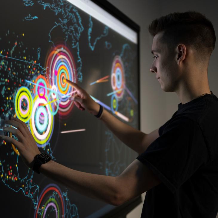 A student uses an interactive screen to visualize data on a map.