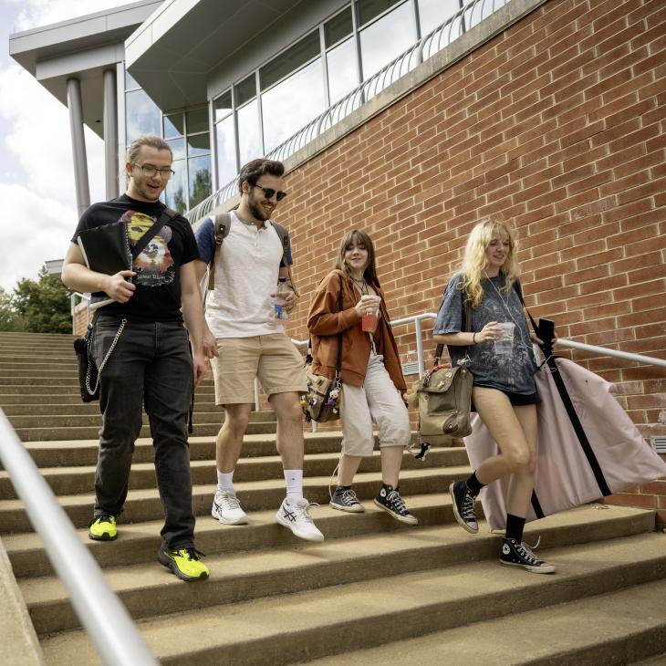 Four students walking down the steps by WPAC.