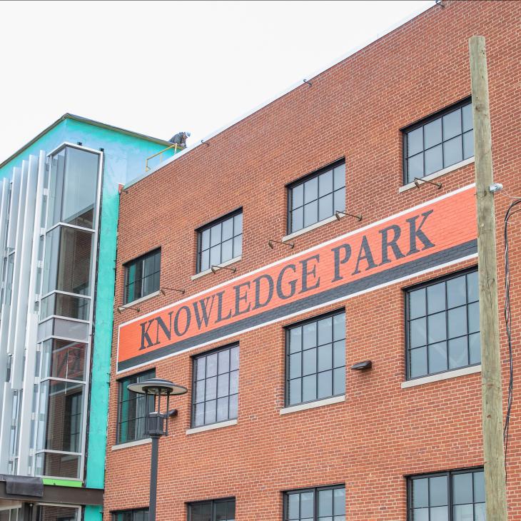 The front of a three-story brick building features a large sign that reads "Knowledge Park."