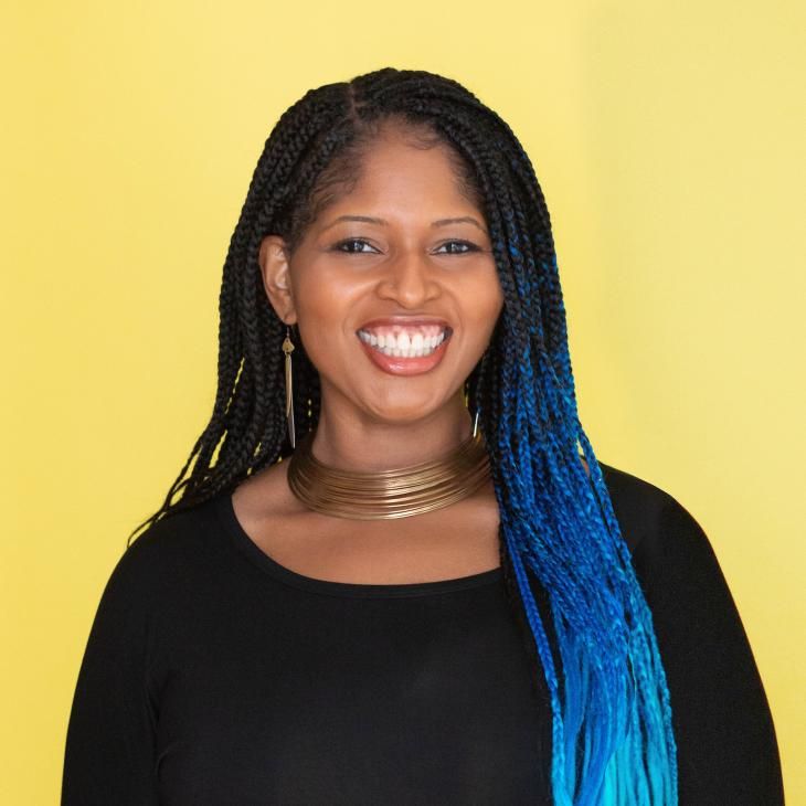 Photo of Mecca Jamilah Sullivan standing in front of a bright yellow background