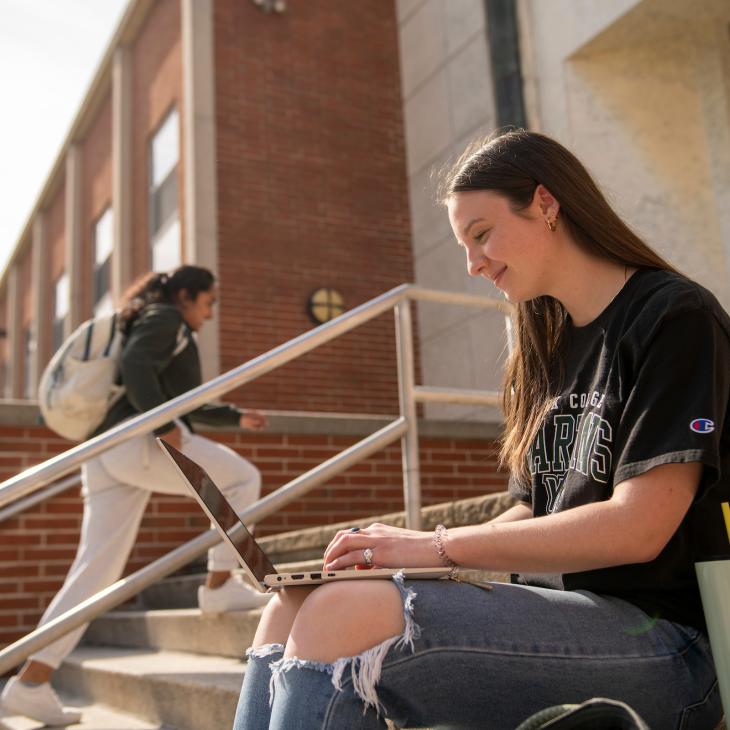 Student on library steps using laptop