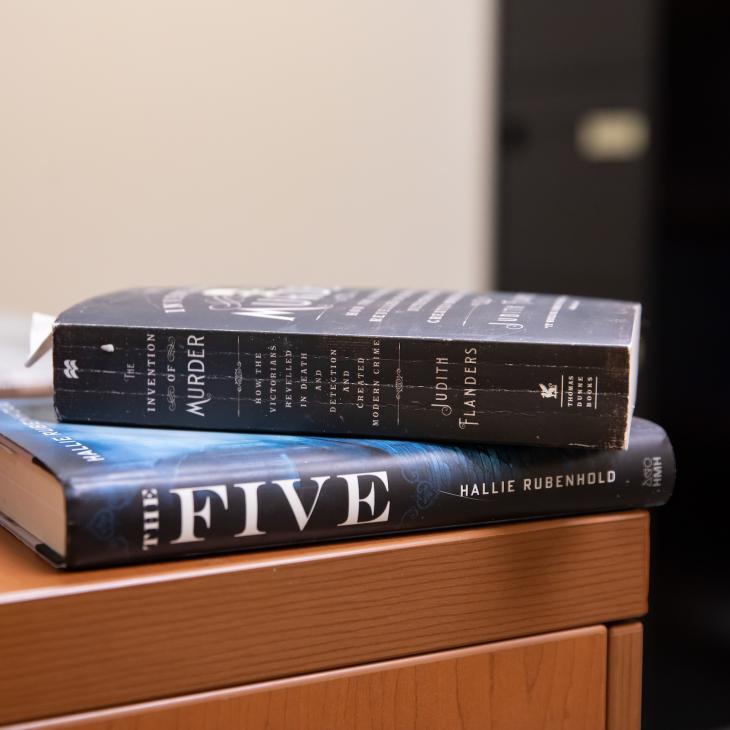 Two books are stacked on the corner of a desk.