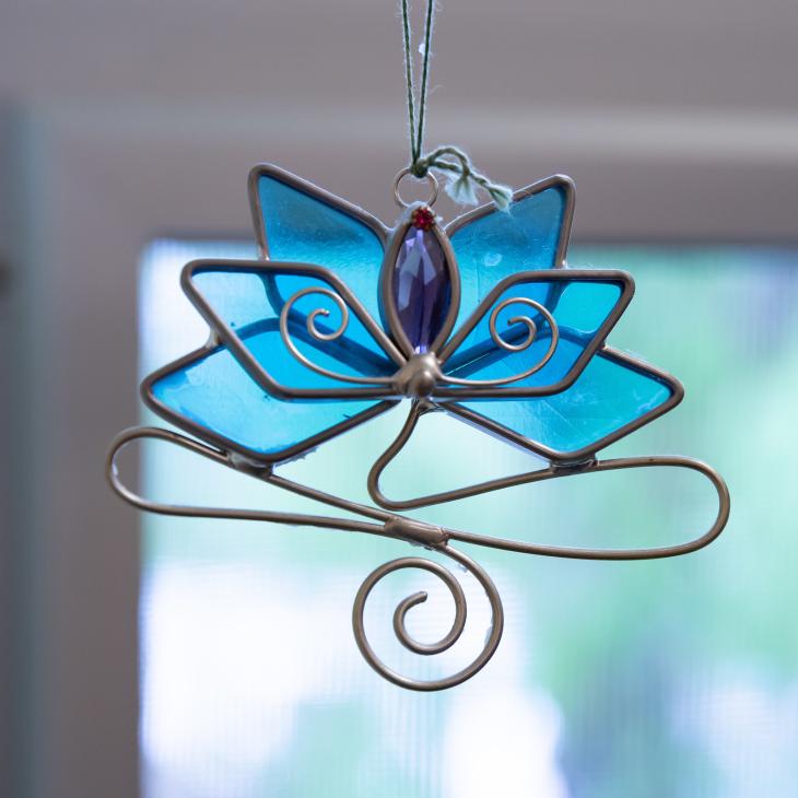 A blue stained glass lotus flower hangs in a window.