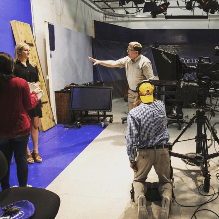 Student in a TV studio learning how to become a broadcaster with instruction from teachers.