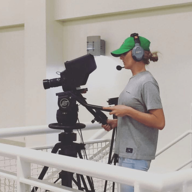 Student operating a camera at a sporting event.