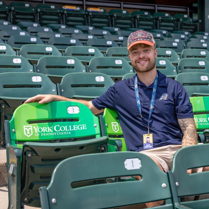 Individual seated in an empty sport stadium.