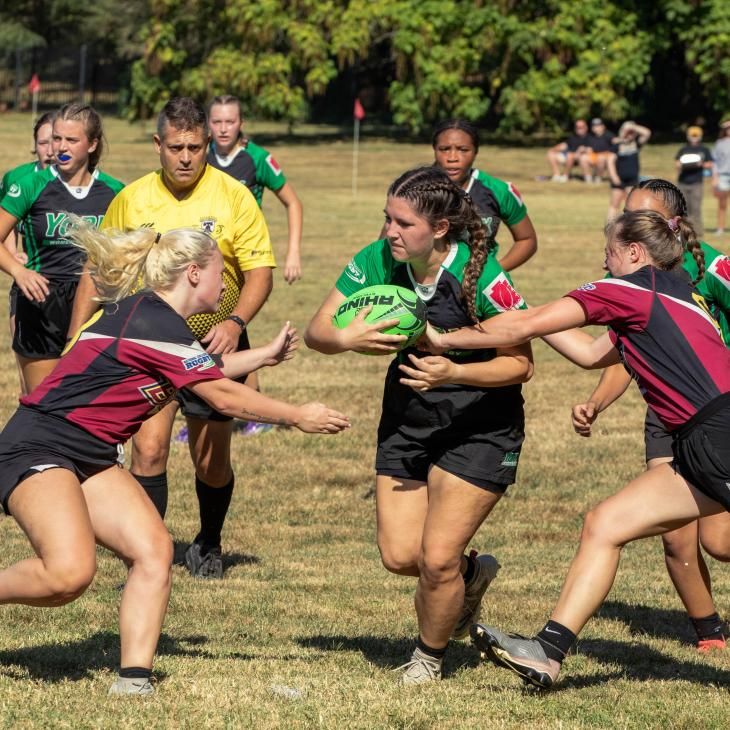 Students engaged in a game of women's rugby.