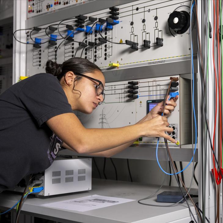 A student hold and examines wires attached to a circuit board.
