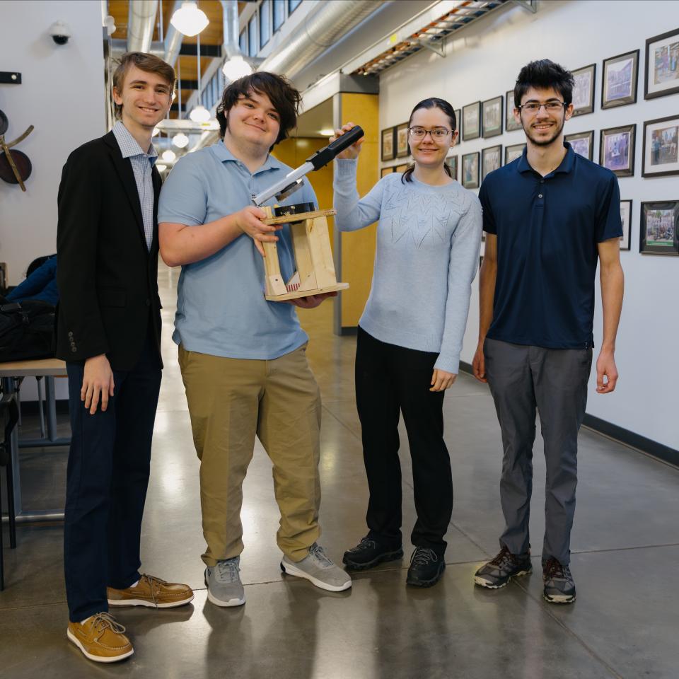A group of four engineering students stand with their presentation.