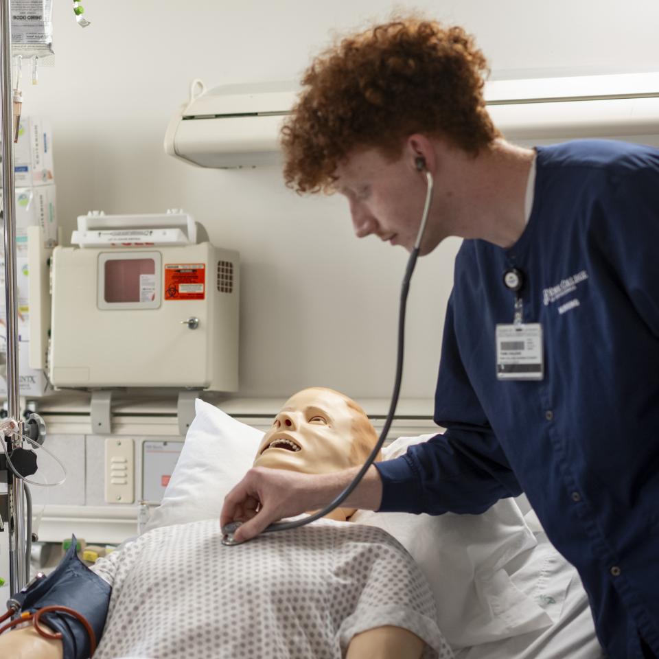 Two student nurses working with a simulator.